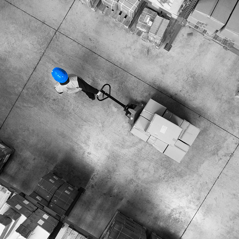 Male warehouse worker pulling a pallet truck.